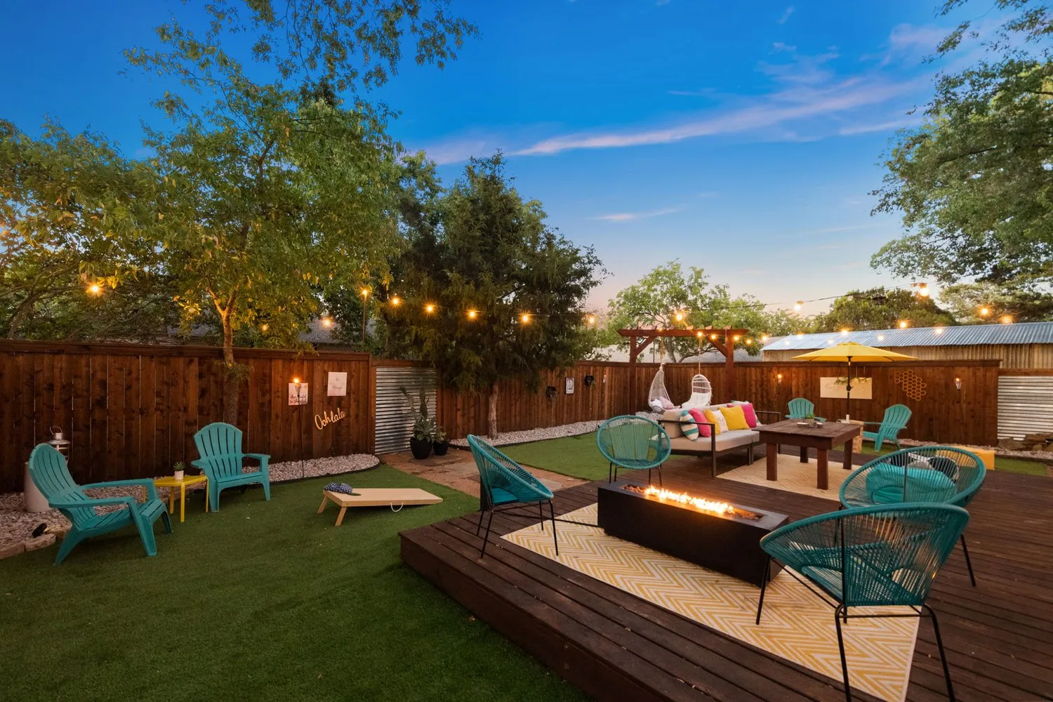 The 139 Olive backyard lit with string lights at dusk, with lounge seating and fire pit